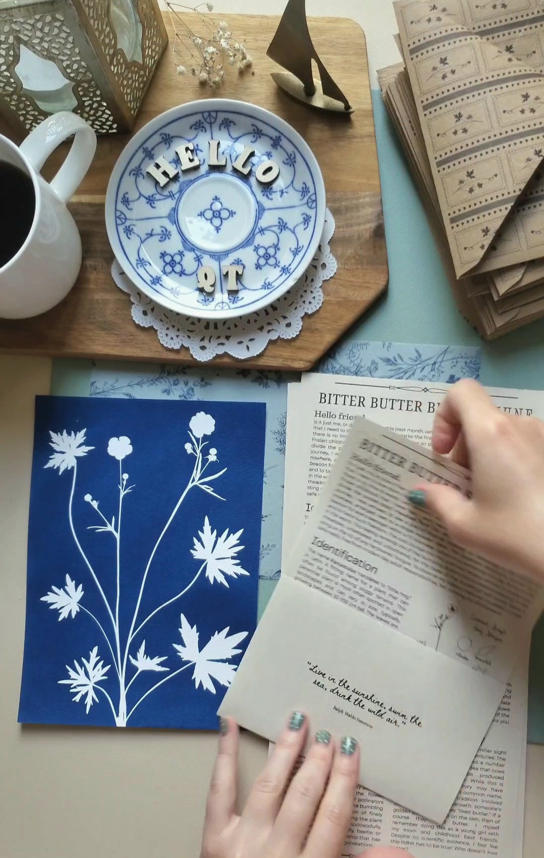 artist folding letters with a cyanotype of a buttercup sitting alongside on the table